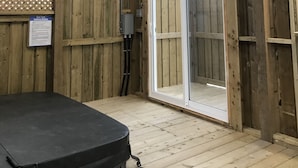 Una habitació de fusta amb una porta corredissa de vidre que dona a l'exterior, un ventilador de sostre i un objecte negre al terra.