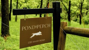 A sign for POND&PERCH at 1310 River Road, surrounded by a wooden fence and lush greenery. - 50-Acre Riverfront Farm – Dog Friendly & Sleeps 6 (Milanville)