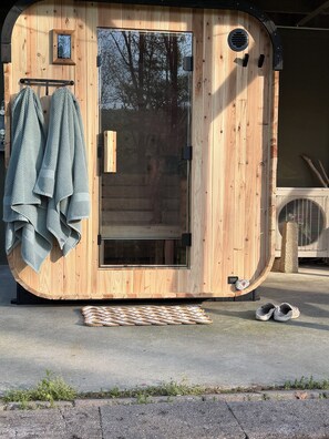 Eine Holzhütte mit Tür, kleinem Fenster und Lüftung.