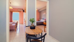 A dining area with a round wooden table, chairs, and a potted plant. - Avouris Deluxe Studio (Zakynthos)