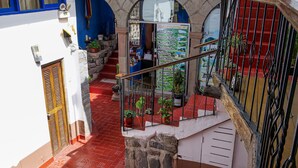 A multi-level building with a red-tiled floor, a staircase with metal railings, and a balcony with potted plants. - Hotel Guest House Wayra Cusco (Cusco)