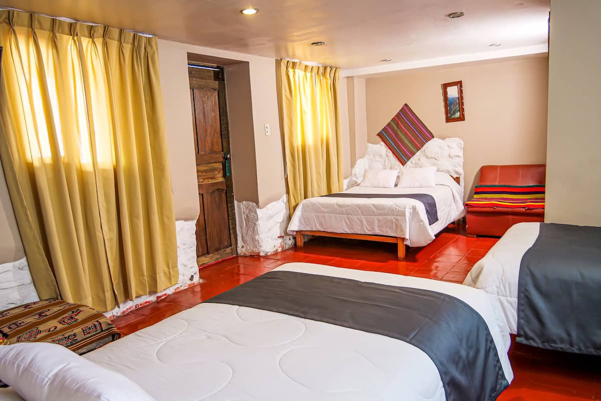 Ein Hotelzimmer mit zwei Betten, einer Holztür und einem roten Ledersofa.