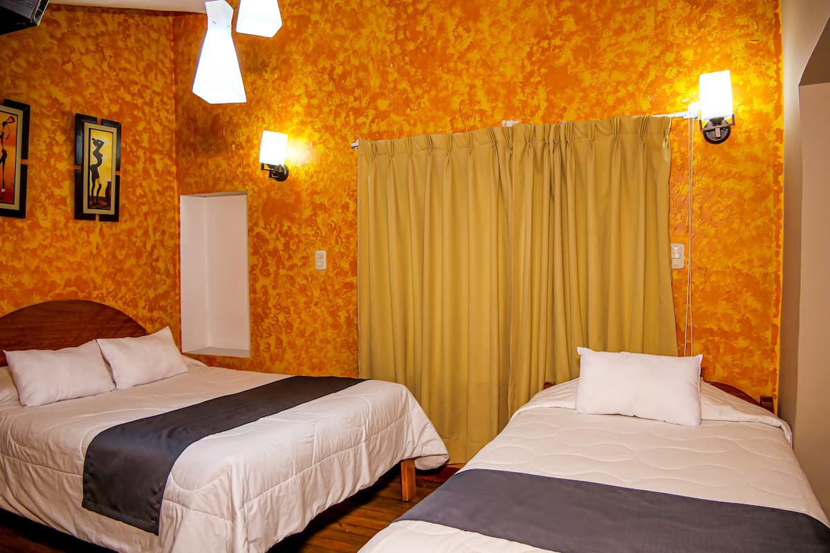 Ein Hotelzimmer mit zwei Betten, Holzboden und einem gelben Vorhang.