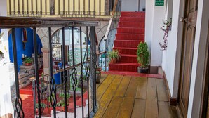 A wooden staircase leading to a red-carpeted area with a metal railing. - Hotel Guest House Wayra Cusco (Cusco)