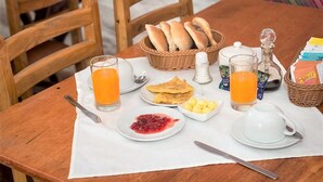 A breakfast table with bread, butter, jam, and juice. - Hotel Guest House Wayra Cusco (Cusco)