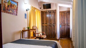 A hotel room with a bed, a desk, a chair, a television, and a wooden door. - Hotel Guest House Wayra Cusco (Cusco)