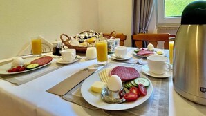 A breakfast table with plates of food, cups, and a thermos. - AM BERG Hotel (Herzberg am Harz)