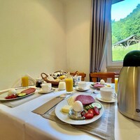 Una mesa de desayuno con platos de comida, tazas y un termo.