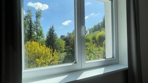 A room with a large window overlooking a forested area. - AM BERG Hotel (Herzberg am Harz)