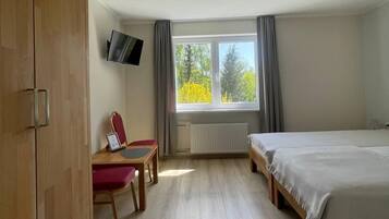 A bedroom with a bed, a desk, a chair, a wardrobe, and a window with curtains.