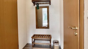 A hallway with wooden flooring, a bench, a trash bin, and a door with a keyhole. - AM BERG Hotel (Herzberg am Harz)