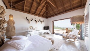 Ein Schlafzimmer mit einem großen Bett, einem Fernseher und Blick ins Freie.