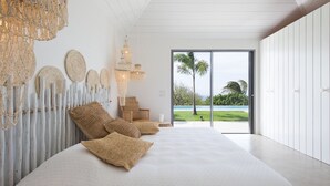 Ein modernes Schlafzimmer mit einem großen Bett, Wandgestaltung aus Gewebe und Blick auf eine tropische Landschaft.