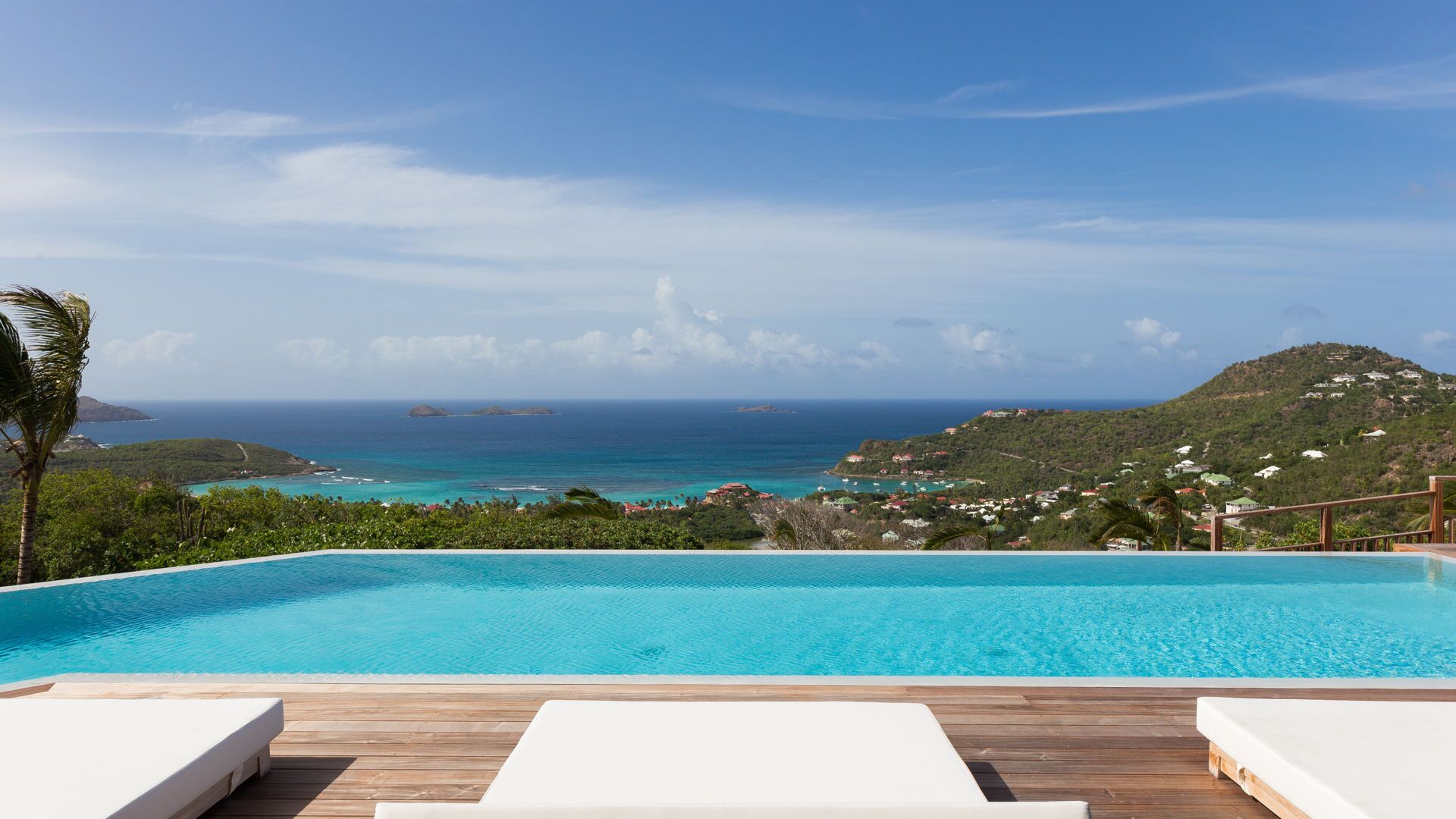 A pool with a view of the ocean and a hilly landscape.