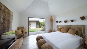 A bedroom with a large bed, a TV, and a view of a garden through a sliding door. - Ixfalia (2/4 Rooms) Luxury villa (St Barts)
