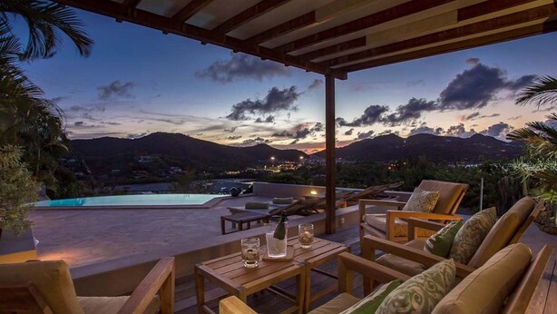 A terrace with wooden furniture, a pool, and a view of mountains at dusk. - Villa Sas (1/2 Rooms) (Saint Jean)
