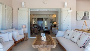 A spacious living room with a wooden coffee table, two sofas, and a dining area with a table and chairs. - Villa Sas Luxury villa (Saint Jean)