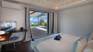 A bedroom with a bed, a desk, a television, and a view of the ocean. - Cairn (3/4 Rooms) Luxury villa (Petit Cul de Sac)