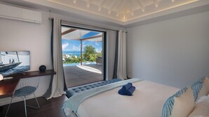 Une chambre avec un lit, un bureau, une télévision et une vue sur l’océan.