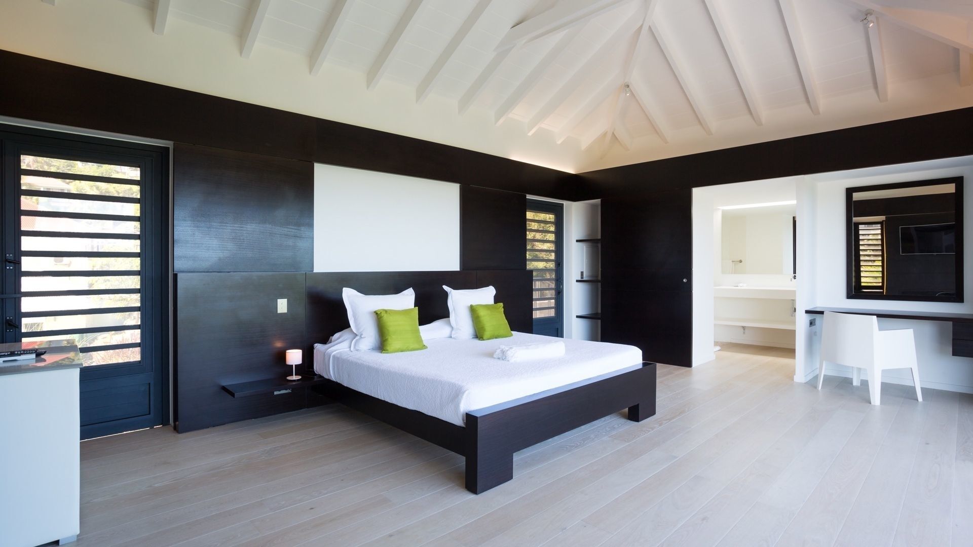 A modern bedroom with a large bed, a desk, and a walk-in closet.