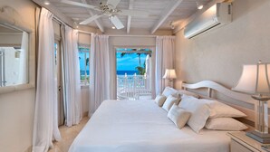 Ein Schlafzimmer mit einem großen Bett, einem Nachttisch, einer Lampe und Meerblick.