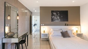 A modern bedroom with a large bed, bedside tables, a desk, and a chair.