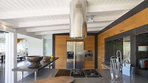 Een moderne keuken met een centraal eiland, roestvrijstalen apparatuur en een grote afzuigkap.