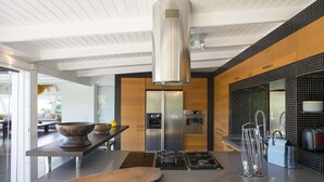 Cozinha moderna com ilha central, eletrodomésticos de aço inoxidável e um exaustor grande.