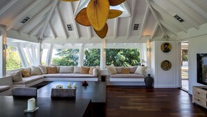Uma sala de estar ampla com teto alto, janelas grandes e ventilador de teto.