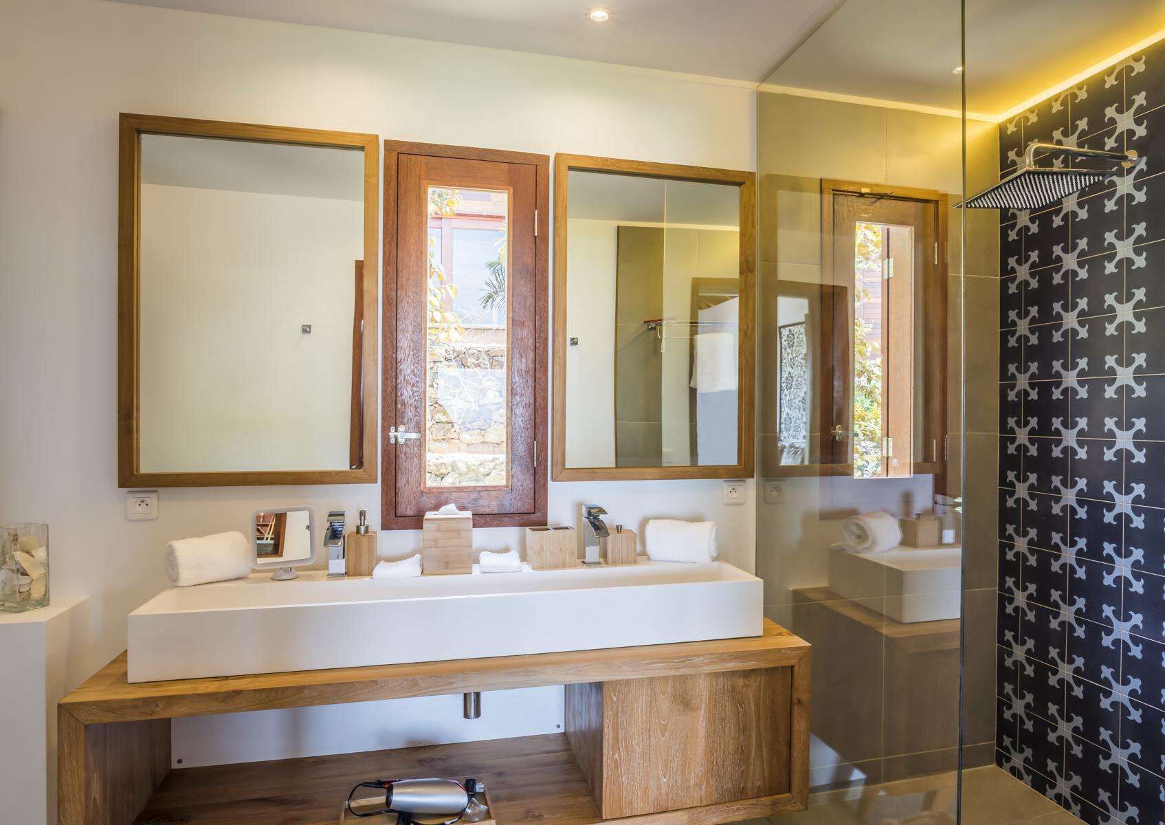 A modern bathroom with a large mirror, a wooden vanity, and a shower with a glass door.