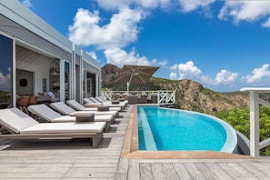 A poolside area with lounge chairs and a view of a mountainous landscape.