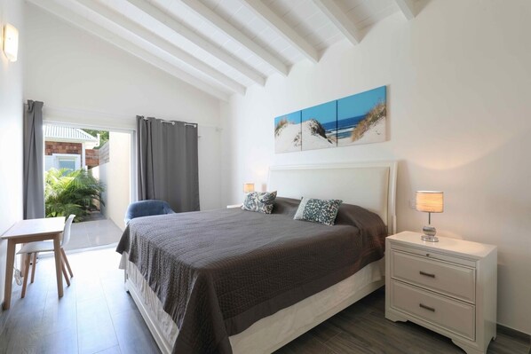 A bedroom with a bed, bedside table, and a painting of a beach scene.