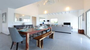 Ein modernes Wohnzimmer mit Essbereich, großen Fenstern und einem Flachbildfernseher.
