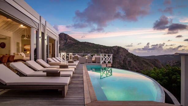 A poolside area with lounge chairs, a wooden deck, and a view of a mountainous landscape. - Beautiful Azetes Luxury villa (Vitet)