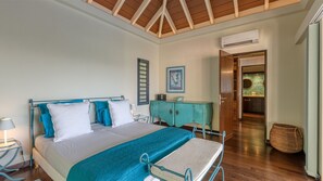 Quarto com cama, mesa de cabeceira, cômoda e porta aberta para um banheiro.