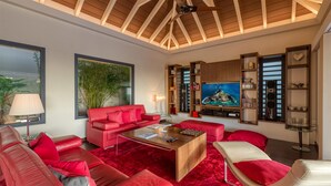 Una sala de estar moderna con un sofá rojo, una mesa de centro de madera y un televisor de pantalla plana grande.
