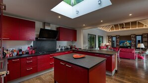 Una cocina moderna con armarios rojos, una isla central y un tragaluz.