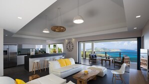 Ein modernes Wohnzimmer mit einem weißen Sofa, einem Holztisch und Blick auf das Meer.