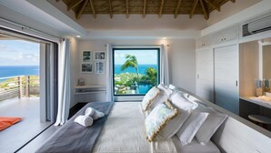 Ein modernes Schlafzimmer mit einem großen Bett, Meerblick und einem Balkon.