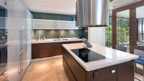 Een moderne keuken met een centraal eiland, roestvrijstalen apparatuur en uitzicht op groen.