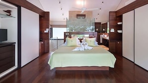 Een ruime slaapkamer met een groot bed, een plafondventilator en uitzicht op de omgeving.