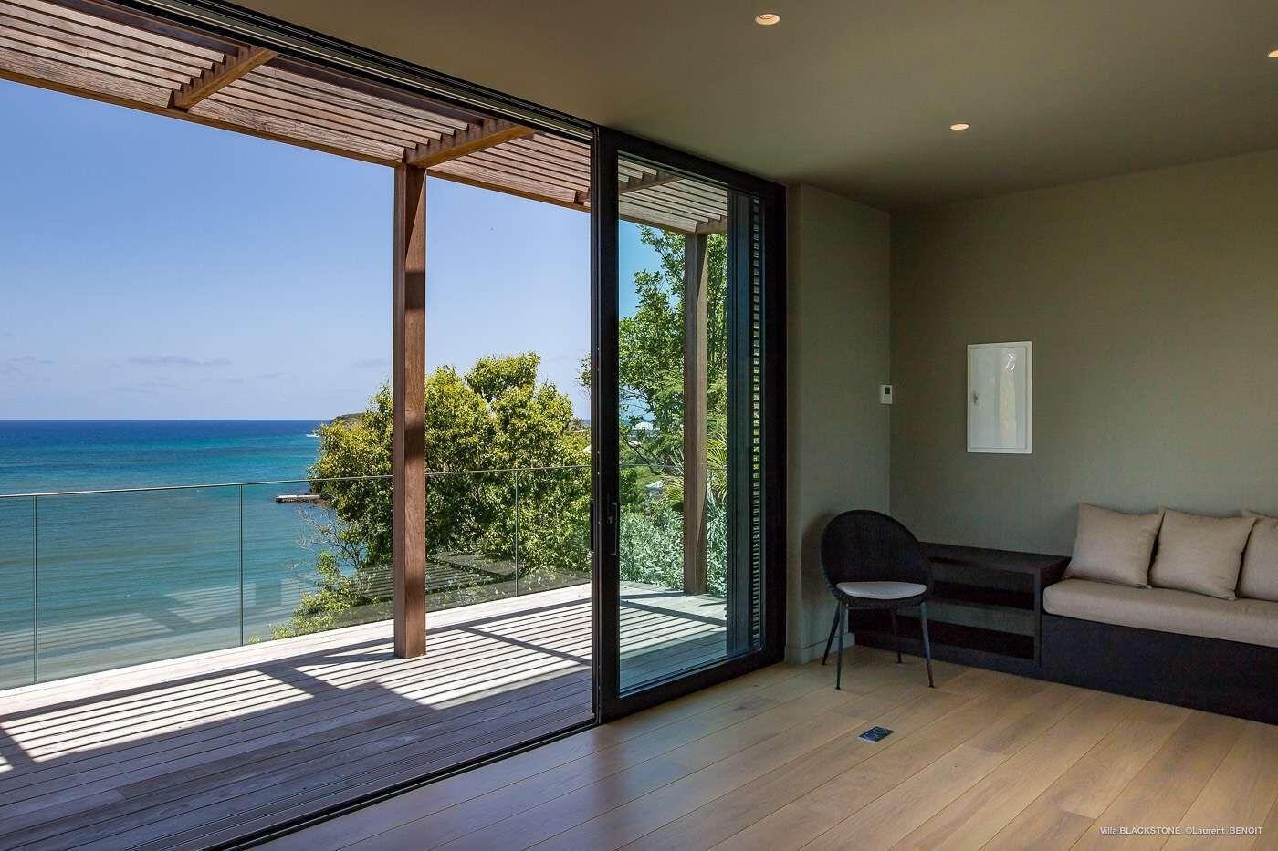 Une chambre moderne dotée d’une grande porte-fenêtre coulissante donnant sur un balcon avec vue sur l’océan.