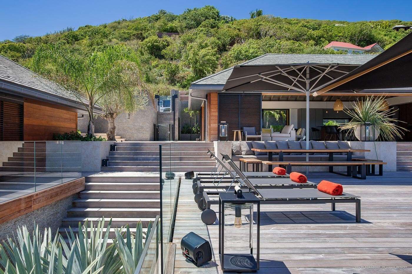 Une terrasse extérieure moderne, dotée d’une piscine, d’une plateforme en bois et de mobilier d’extérieur.