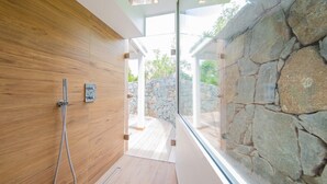 A modern bathroom with wooden walls, a stone wall, and a glass door leading outside. - Lenalee (1/4 Rooms) Luxury villa (Gustavia)