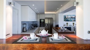 Une cuisine moderne avec un coin repas, comprenant un réfrigérateur, un four et une machine à café.