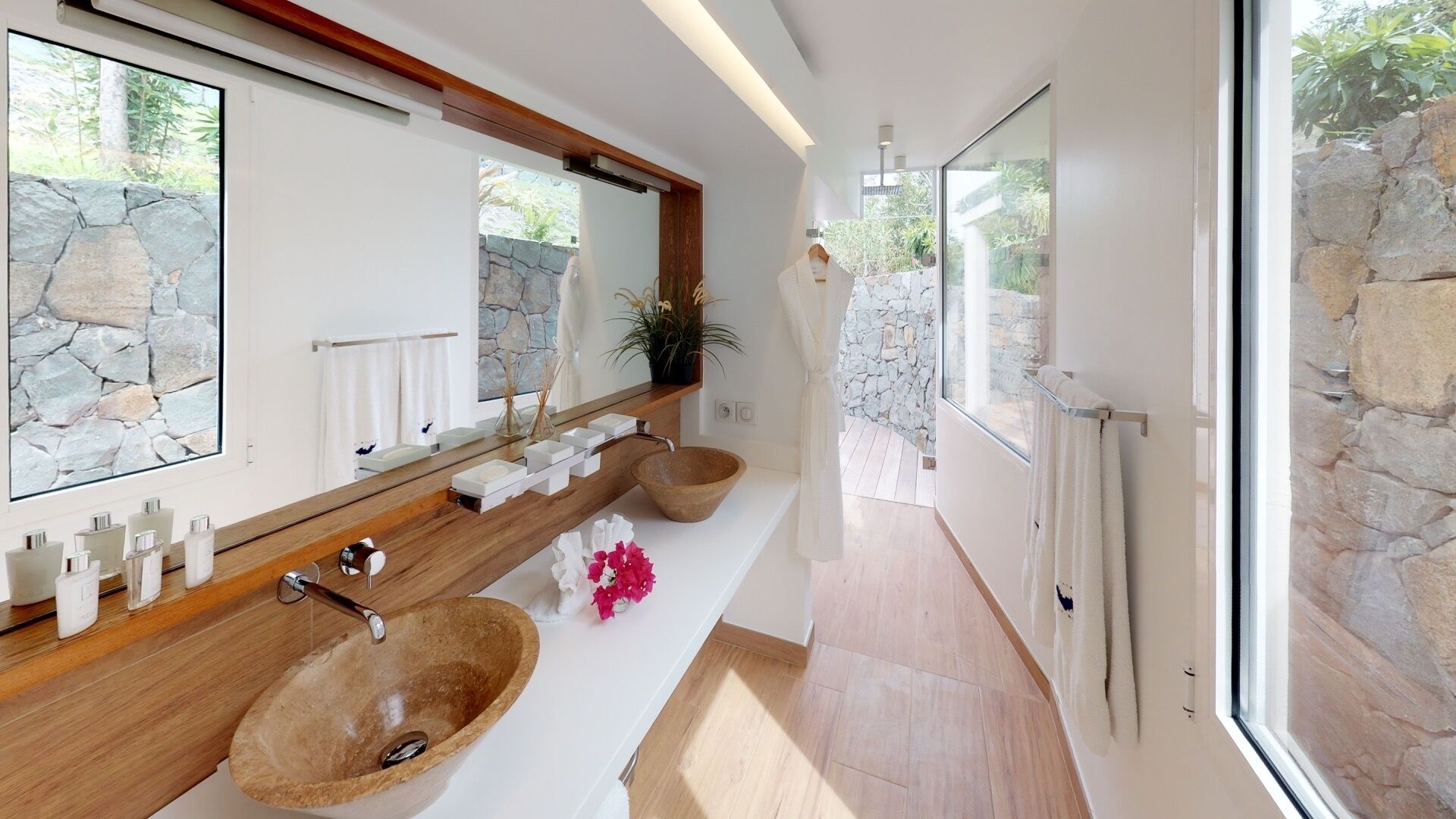 Une salle de bain moderne avec un mur en pierre, un meuble-lavabo en bois et un grand miroir.