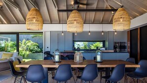 A modern kitchen with a large island, pendant lights, and a view of lush greenery. - Blackstone (4/6 Rooms) (Marigot)