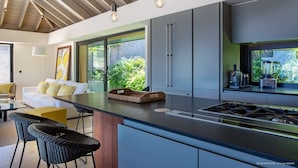 A modern kitchen with a central island, built-in appliances, and large windows offering views of greenery. - Blackstone (4/6 Rooms) (Marigot)