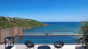 A poolside area with a view of the ocean, lounge chairs, and a wooden deck. - Blackstone (4/6 Rooms) (Marigot)