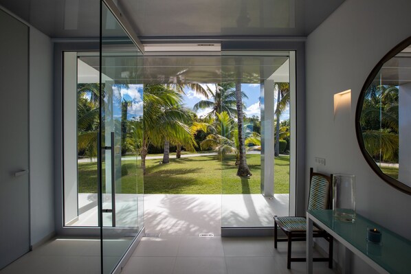 Una stanza moderna con un'ampia porta vetrata che si apre su una vista di giardino tropicale.